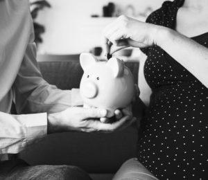 pregnant woman putting money in piggy bank held by man