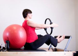 An image of a pregnant woman with her back on an exercise ball, performing an arm workout.