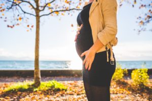 Pregnant woman standing outside in the fall.